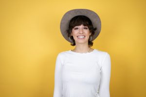 Young caucasian woman wearing hat over isolated yellow backgroun